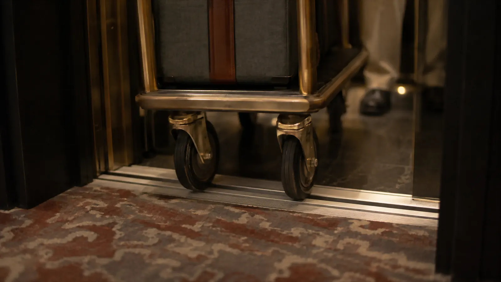Folding luggage cart wheels crossing the gap of a hotel elevator threshold